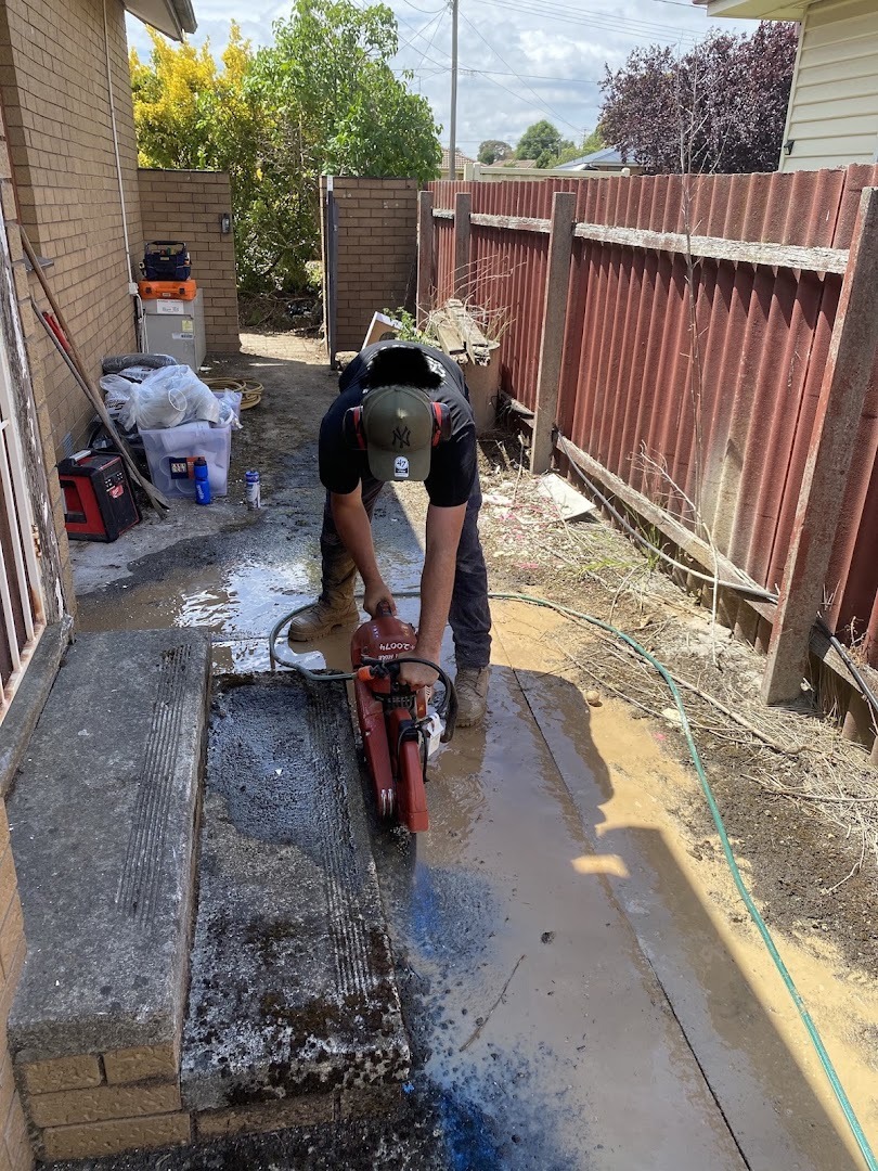 A Fast Fix plumber cutting a concrete path with a demolition saw to reach a Ballarat drain line