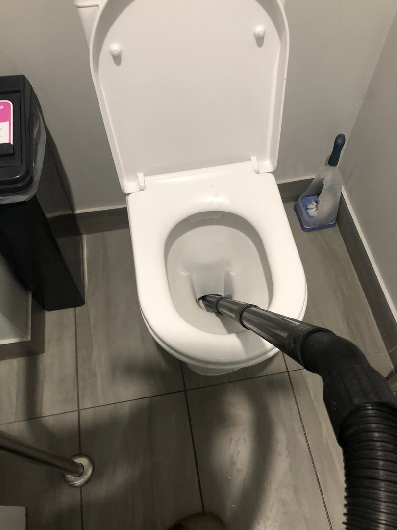 A drain machine hose fed into a toilet pan in a tiled Ballarat bathroom