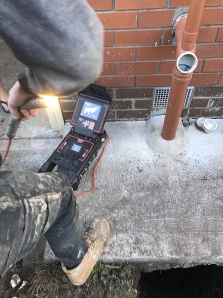 A drain camera monitor and reel set up beside an opened drain at a Ballarat house
