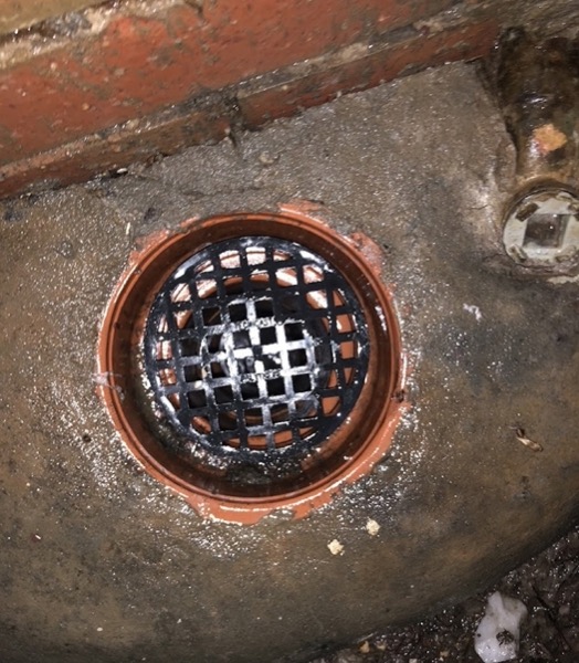 An orange gully and its grate opened up at ground level