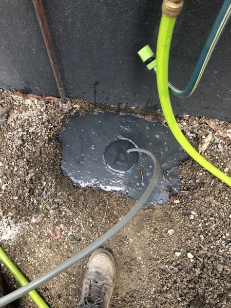 A jetting hose fed into a ground-level drain access point