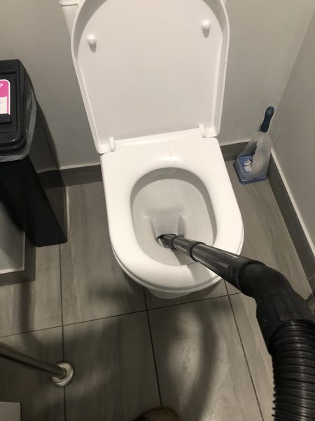 A drain machine hose fed into a toilet pan in a tiled Ballarat bathroom