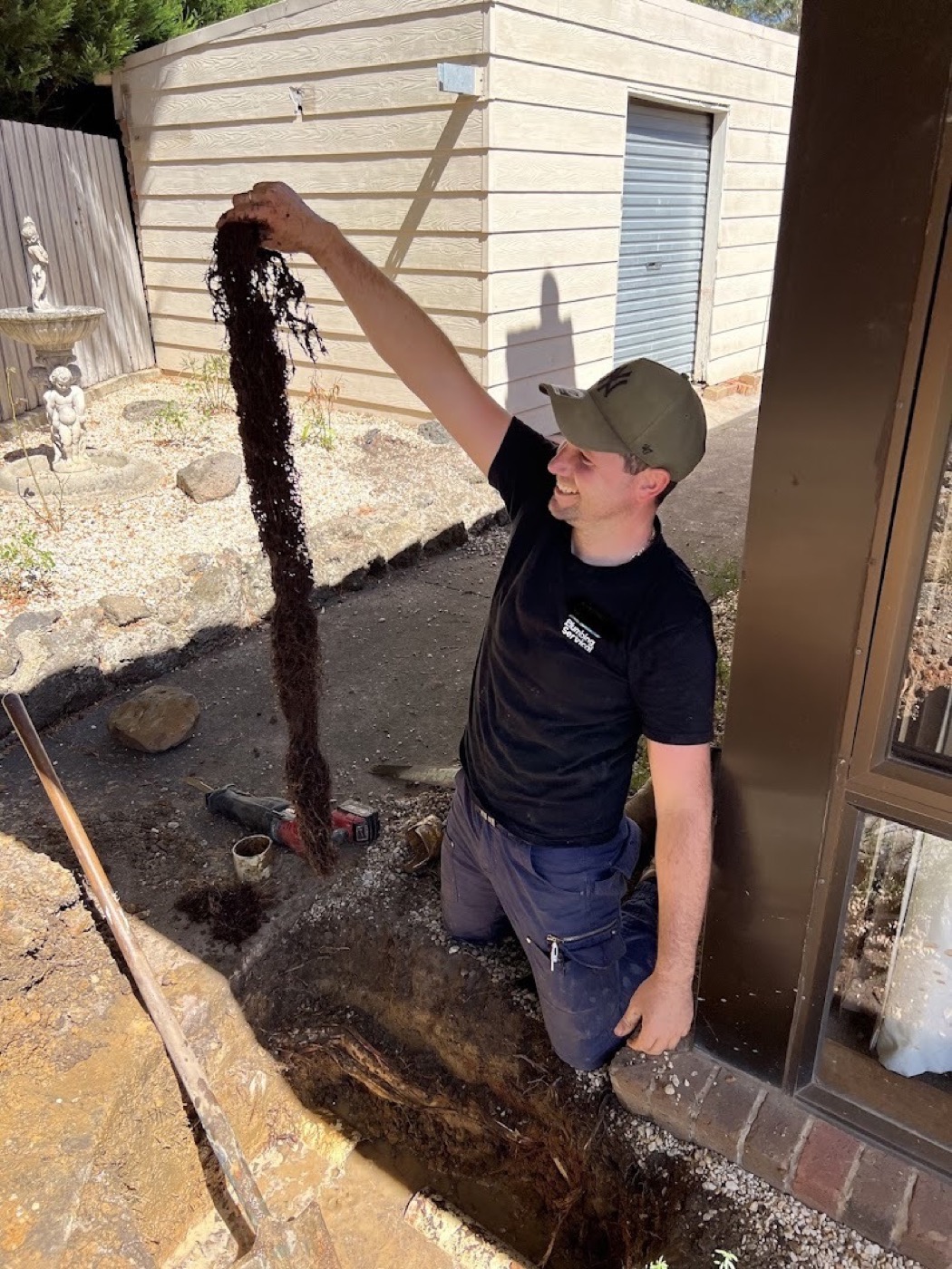 A Fast Fix plumber lifting a mass of tree roots pulled out of a Ballarat drain